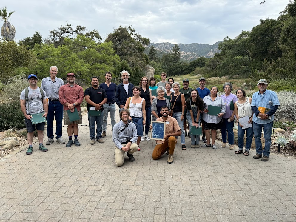 A large group of people smiling and proudly holding their certification for completing the CA Native Plant Landscaper Program