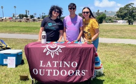 Three Latino outdoor leaders at table in park at outdoor event