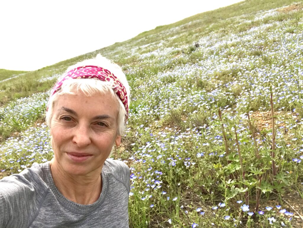 Woman hiking and stops for picture with California native wildflower