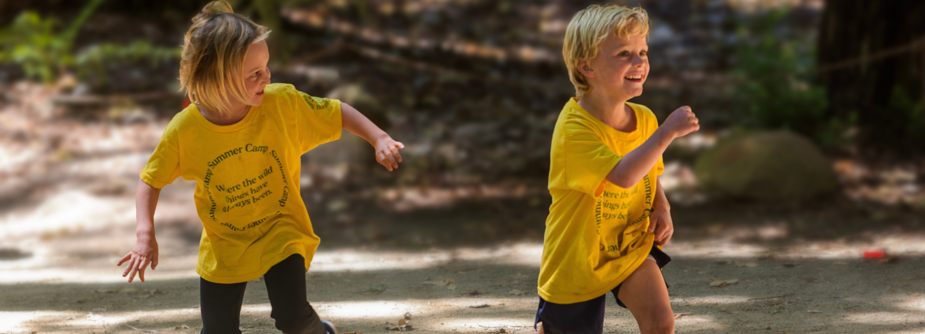 Dos niños con camisetas amarillas corriendo al aire libre, sonriendo.