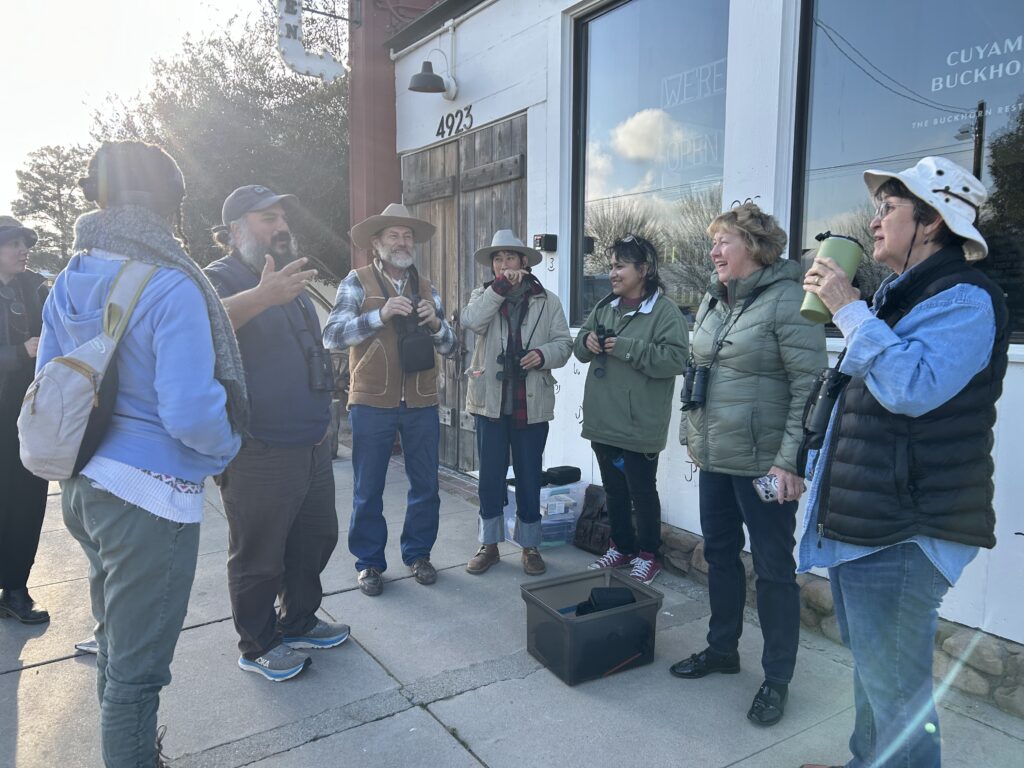 A group of birders standing in a circle to discuss the birding event